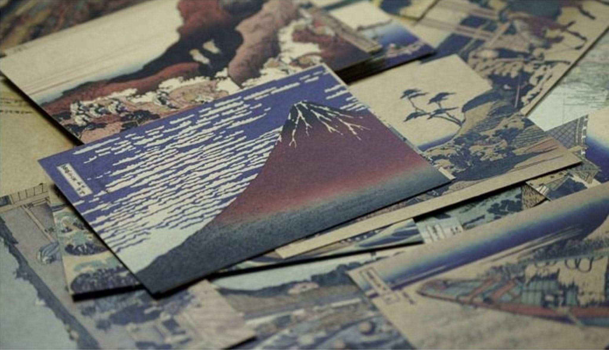 Hokusai Japanese Art Postcards: Ukiyo-E scenes in blue, red, and earth tones on textured paper.